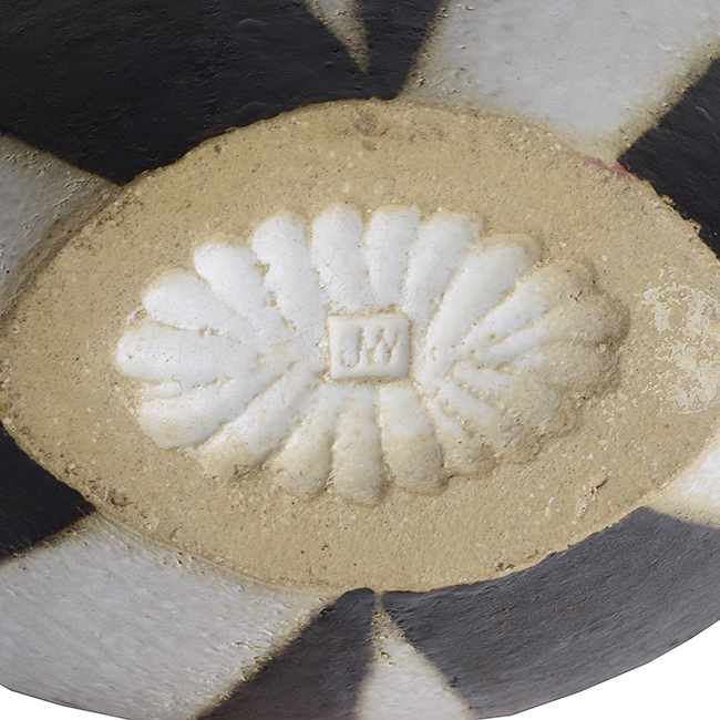 An impressed JW seal on a black and white stoneware pot made by John Ward